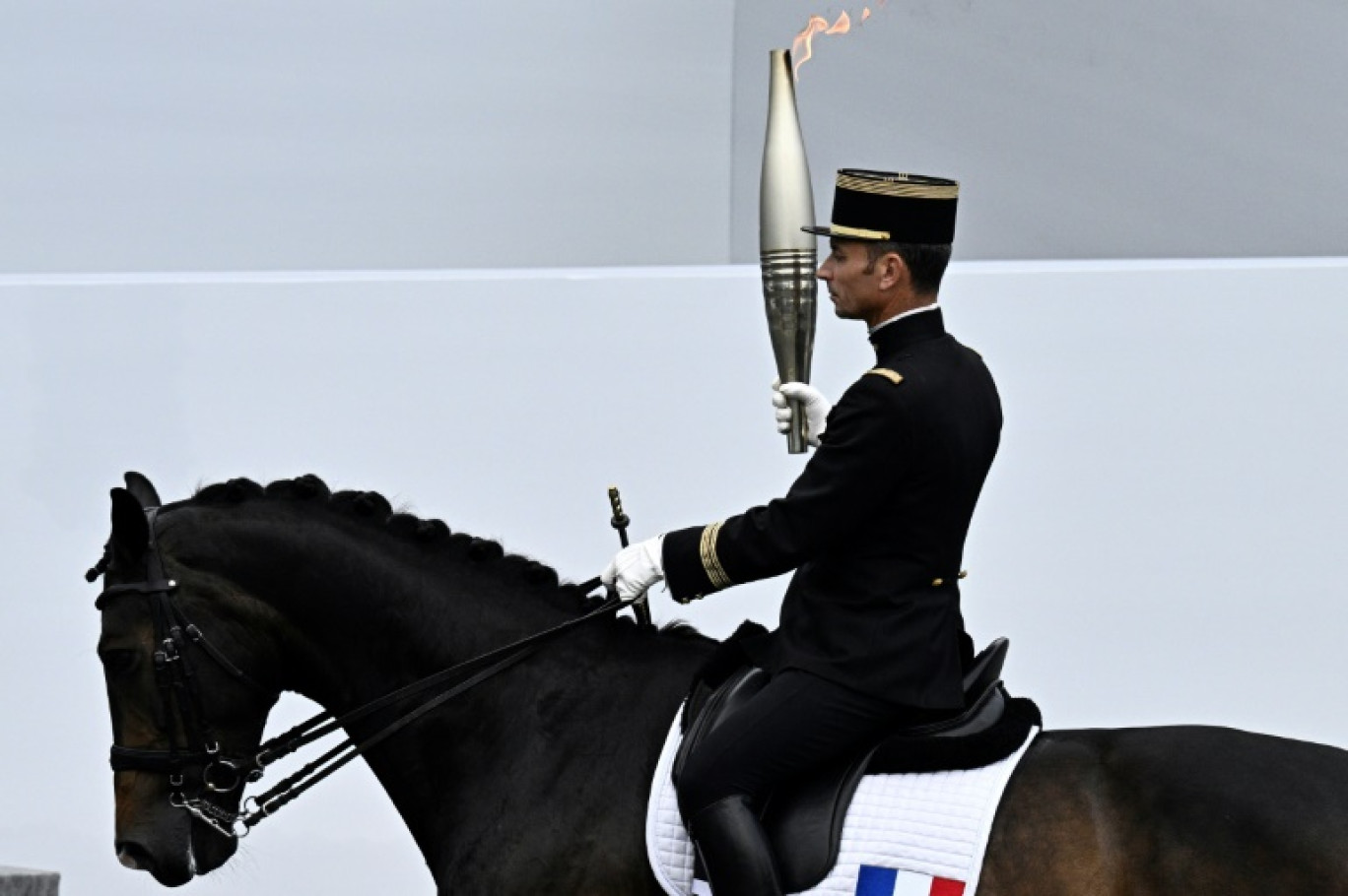 L'ex-international français de football Thierry Henry porte la flamme olympique entre le patron du comité d'organisation des JO de Paris Tony Estanguet et la maire de Paris, Anne Hidalgo, le 14 juillet 2024 à Paris © STEPHANE DE SAKUTIN