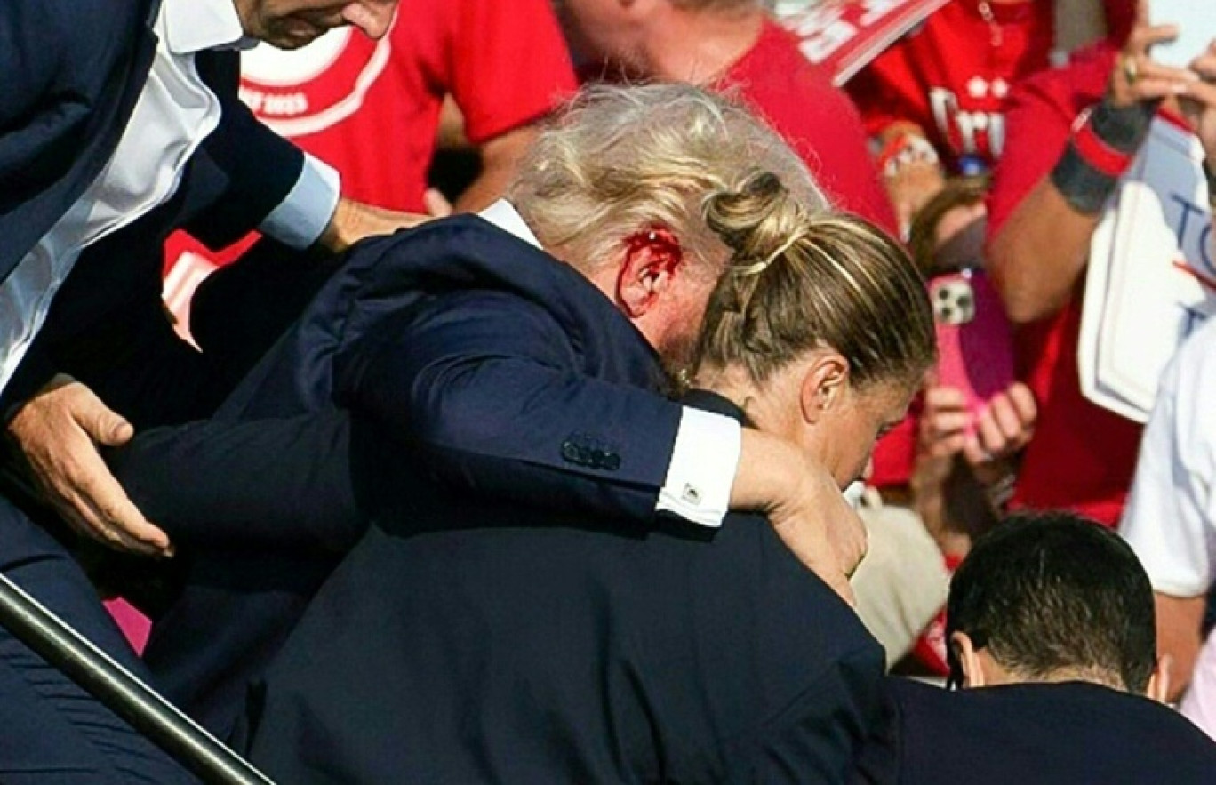 L'ancien président américain Donald Trump, blessé à l'oreille, est escorté hors de scène après tentative d'assassinat lors de son meeting à Butler), le 13 juillet 2024 en Pennsylvanie © Rebecca DROKE