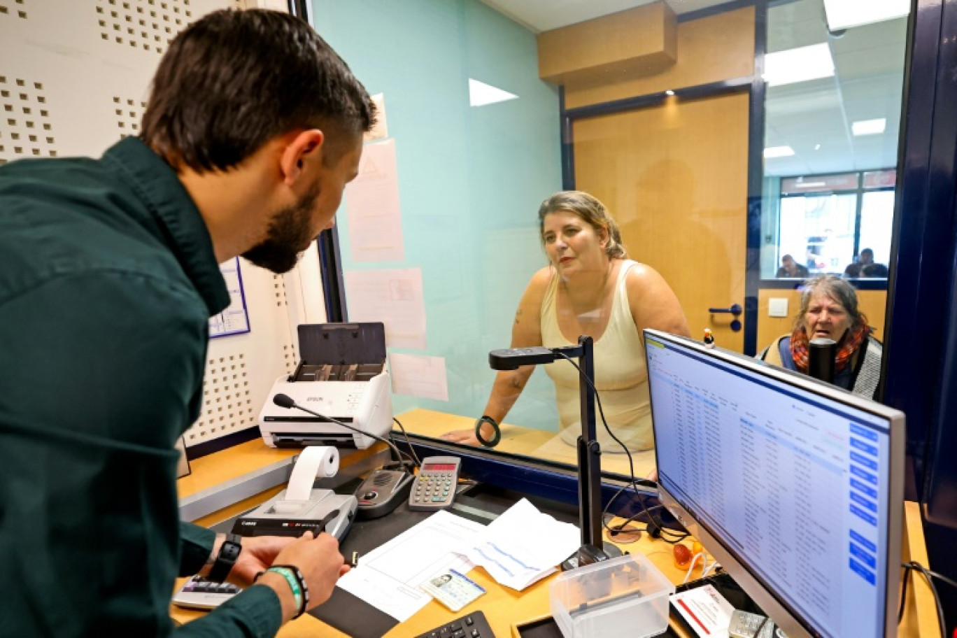 Un employé du Crédit Municipal explique à des clientes le montant proposé par un expert concernant divers objets déposés, le 16 juillet 2024 à Lille, dans le Nord © FRANCOIS LO PRESTI