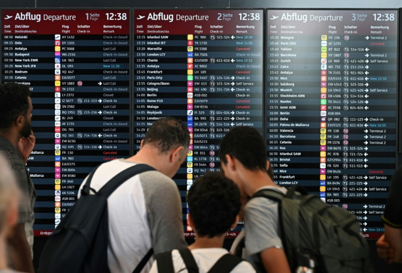 Des passagers consultent un tableau d'information sur les vols à l'aéroport de Berlin, pendant une panne informatique mondiale, le 19 juillet 2024 © RALF HIRSCHBERGER