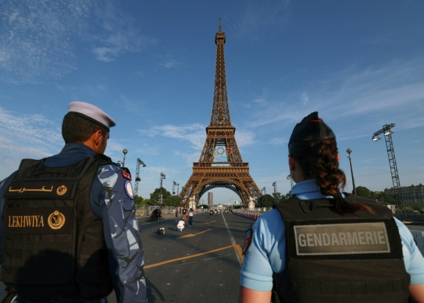 Un membre d'une force de sécurité qatarie (gauche) et une gendarme française se tiennent près de la tour Eiffel, le 18 juillet 2024 à Paris © EMMANUEL DUNAND