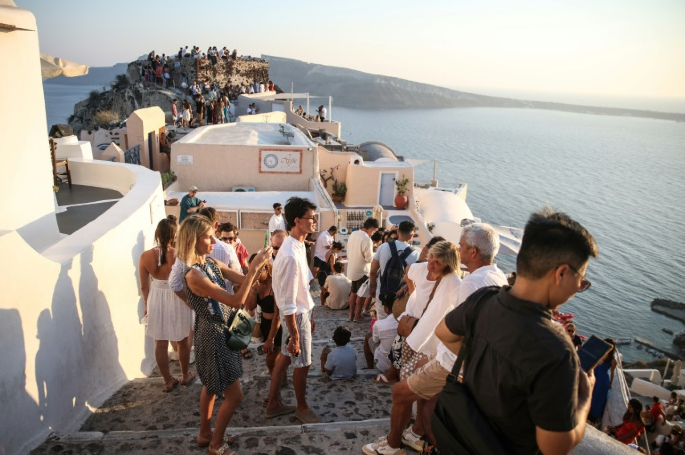 Des touristes attendent le coucher du soleil dans le village d'Oia sur l'île grecque de Santorin, le 20 juillet 2024 © Aris Oikonomou