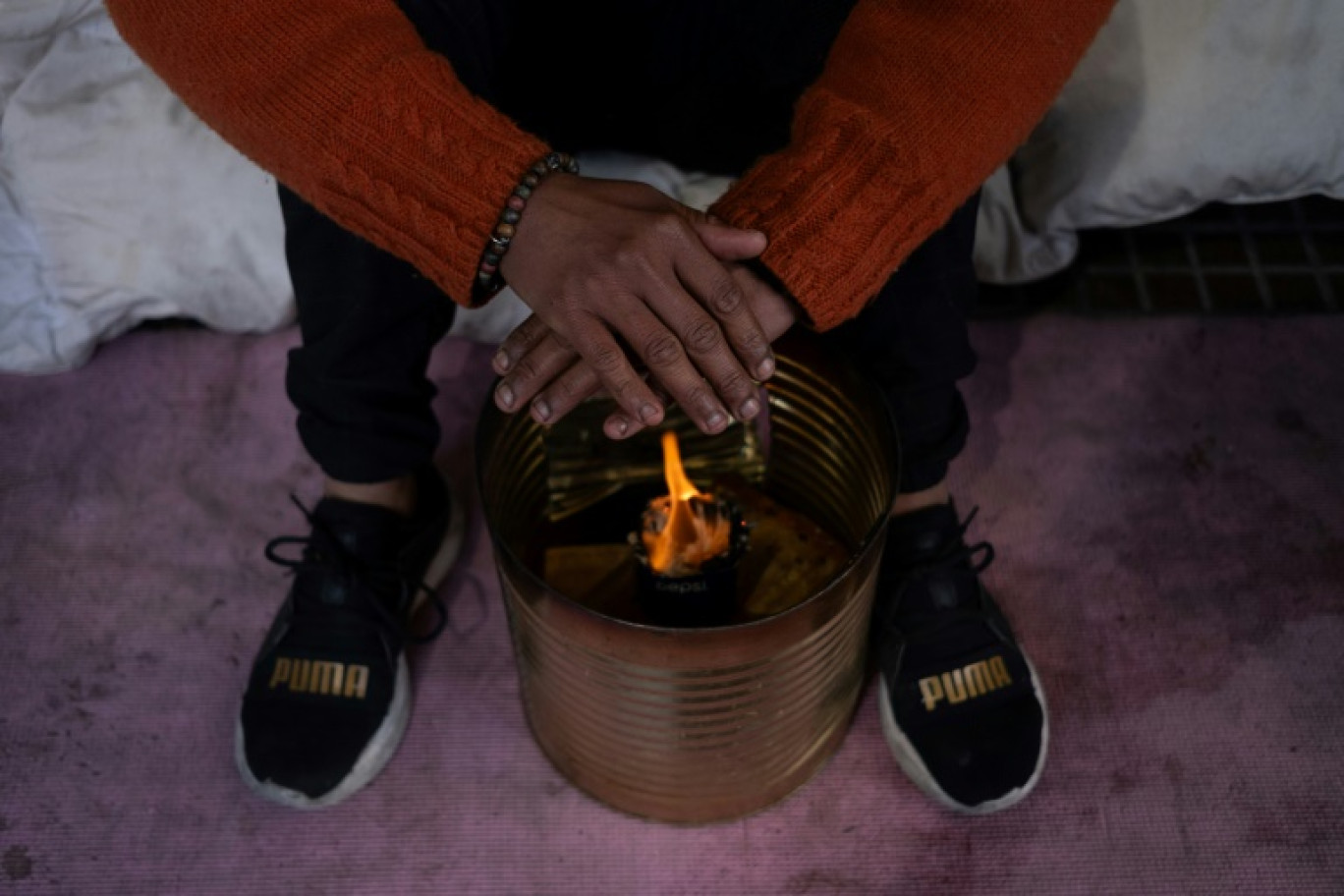 Maria de los Angeles Lopez, une femme sans-abri, se réchauffe les mains sur un brasero dans une rue de Buenos Aires, le 10 juillet 2024 © ALESSIA MACCIONI