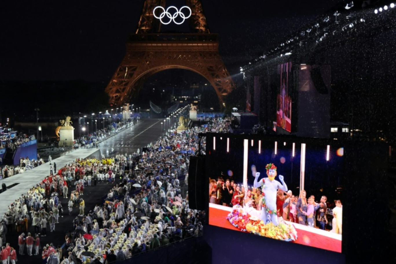 Les délégations arrivent au Trocadéro alors que les spectateurs regardent le chanteur français Philippe Katerine se produire sur un écran géant lors de la cérémonie d'ouverture des JO-2024 à Paris le 26 juillet 2024 © Ludovic MARIN