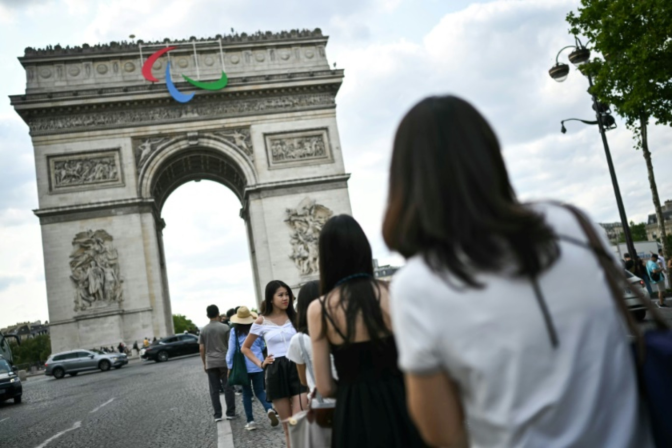 Des touristes posent devant l'Arc de Triomphe à Paris, le 24 juillet 2024 © Ben STANSALL