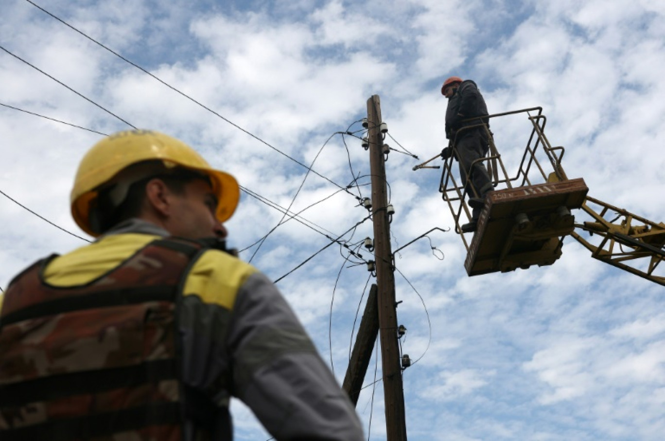 Des électriciens de la compagnie DTEK Energy réparent les lignes électriques endommagées par les bombes dans un village près de la ligne de front dans la région de Donetsk, en Ukraine, le 23 juillet 2024 © Anatolii STEPANOV