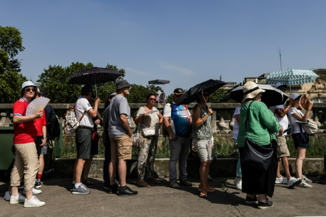 Des promeneurs se protègent du soleil, le 30 juillet 2024 à Paris © Thibaud MORITZ