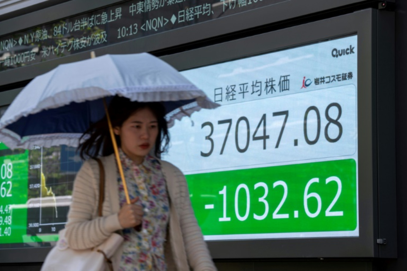 Une femme passe devant un panneau électronique affichant le cours de l'indice Nikkei de la Bourse de Tokyo dans une rue de Tokyo, le 19 avril 2024 © Kazuhiro NOGI