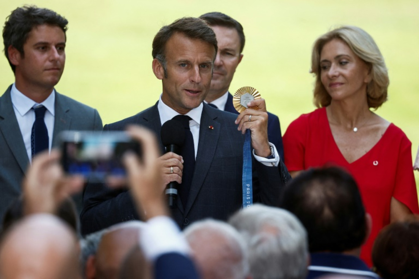 Le président de la République Emmanuel Macron, au centre, tient une médaille d'or des Jeux de Paris 2024, le 12 août 2024, à Paris © Benoit Tessier