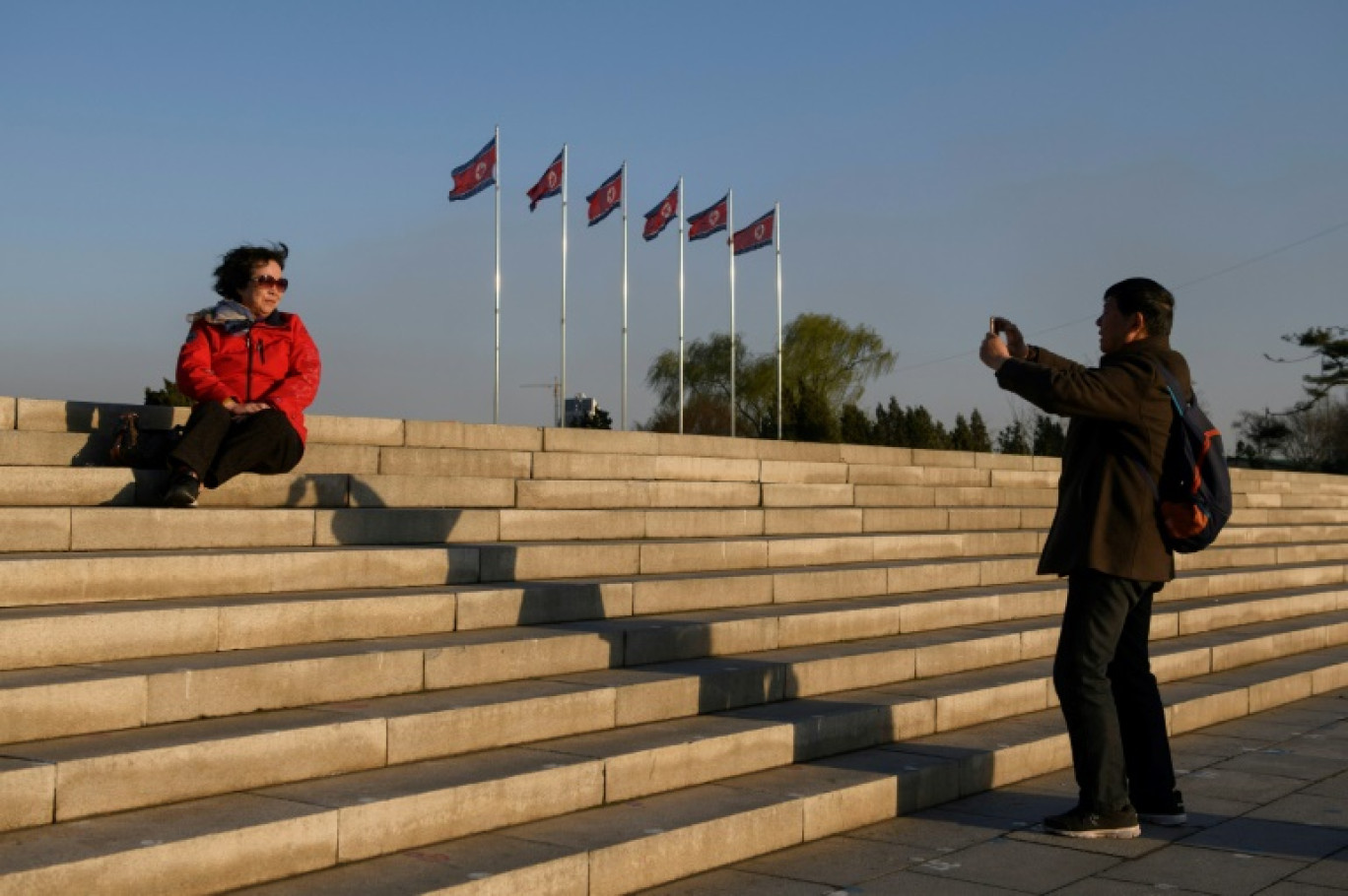 Une touriste chinoise pose pour une photo sur la place Kim Il Sung à Pyongyang, le 14 avril 2019 © Ed JONES