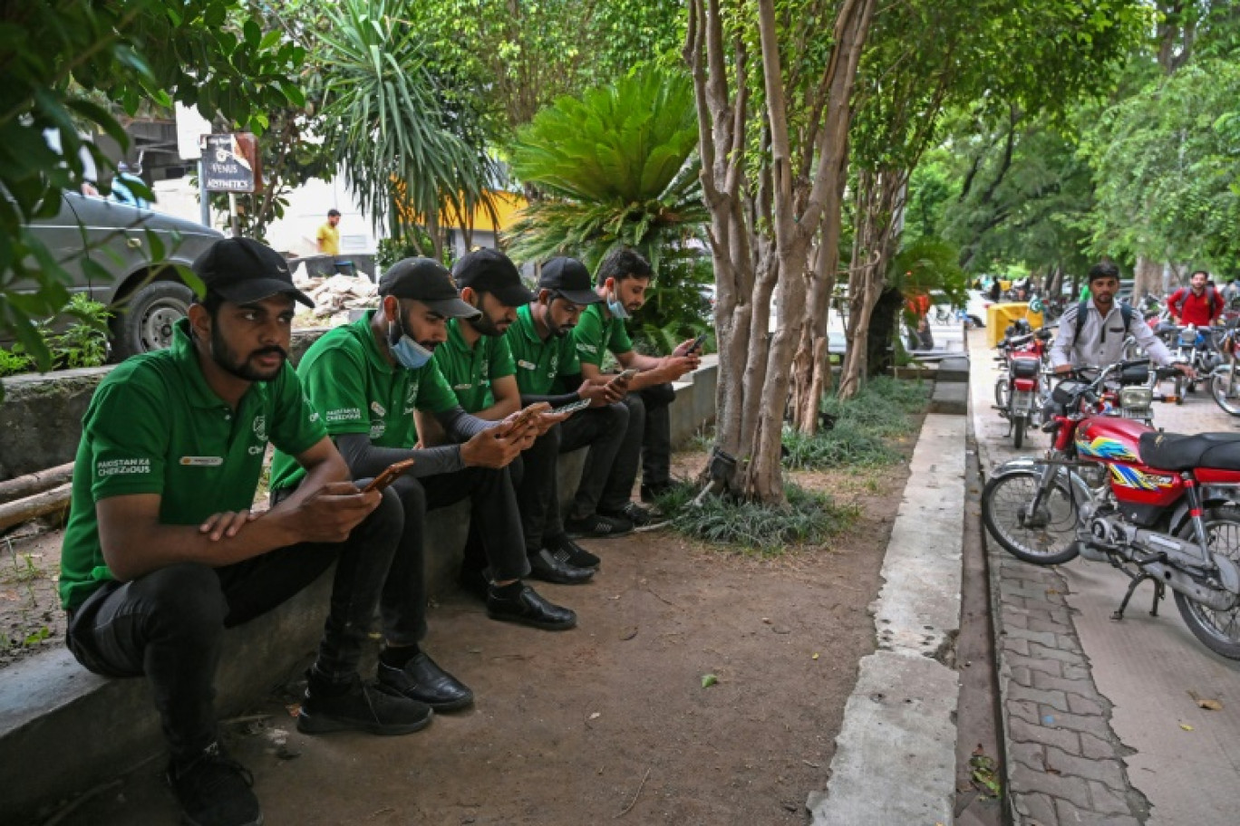 Des livreurs utilisent leurs téléphones portables, à Islamabad, le 17 août 2024 © Aamir QURESHI