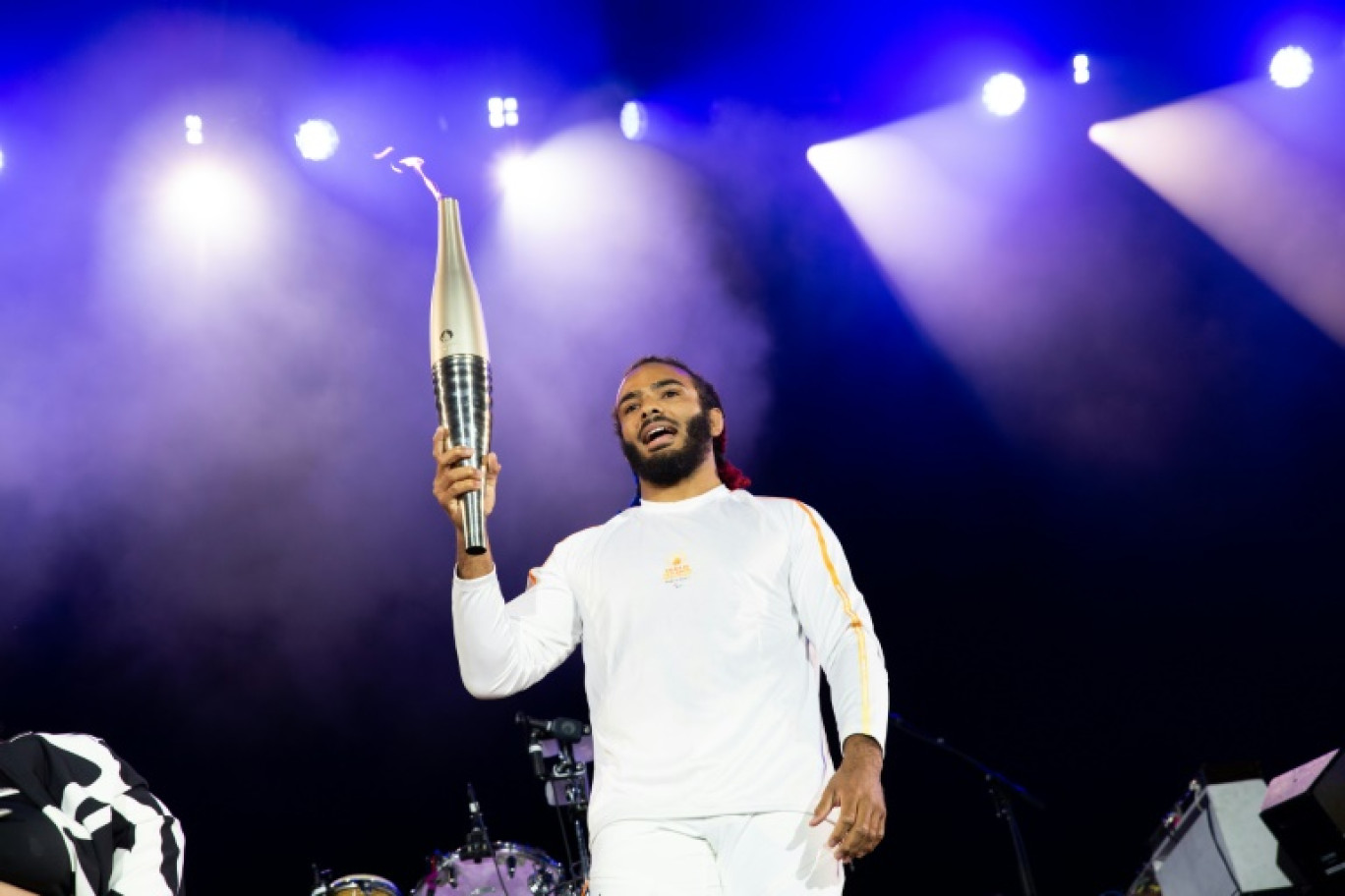 Le judoka français handisport Helios Latchoumanaya porte la flamme des  Jeux paralympiques à Saint-Cloud, dans la banlieue de Paris le 25 août 2024 © Anna KURTH