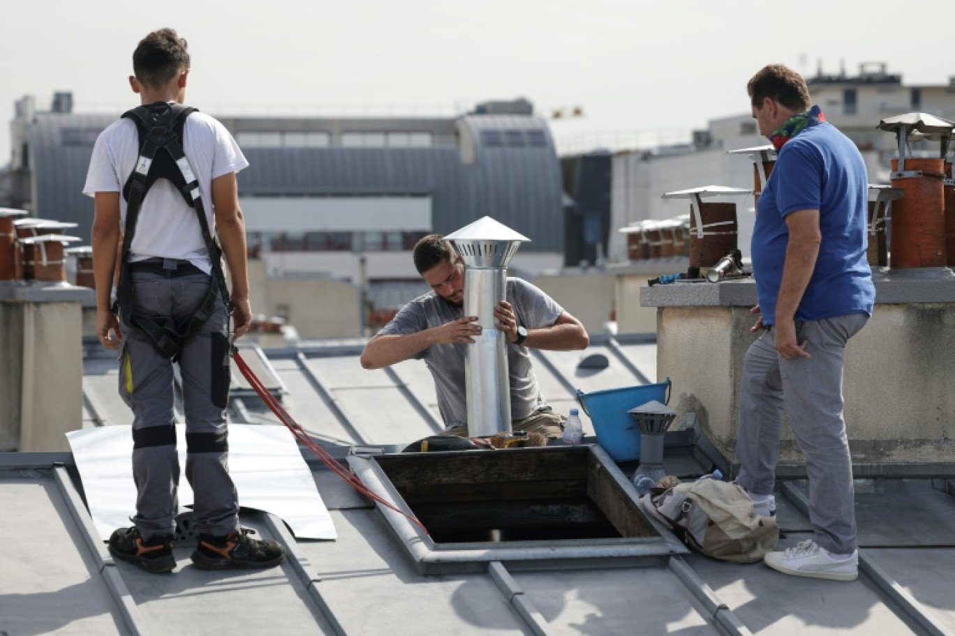 Des couvreurs-zingueurs créent une ventilation sur le toit d'un immeuble couvert de zinc à Paris, le 31 juillet 2024 © Valentine CHAPUIS