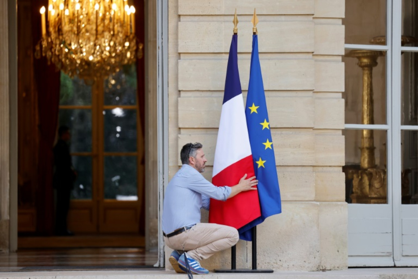 Un homme arrange les drapeaux à l'entrée de l'Hôtel de Matignon, le 30 juin 2024 © Ludovic MARIN