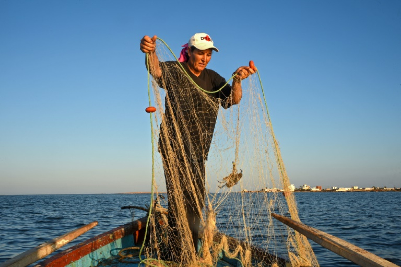 La pêcheuse tunisienne Sara Souissi prépare son filet près de la côte des îles Kerkennah, au sud de Tunis, le 8 août 2024 © Mohamed KHALIL