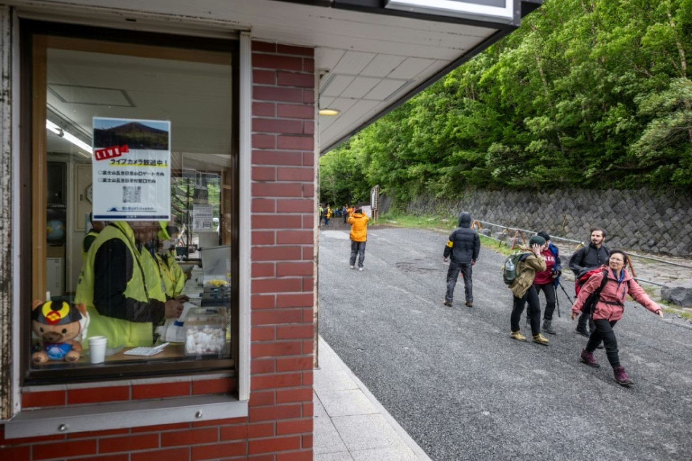 Des randonneurs passent devant le centre administratif de la 5e station de la ligne Fuji Subaru, qui mène au sentier Yoshida pour escalader le mont Fuji, au premier jour de la saison avec les nouvelles mesures de droits d'entrée, le 1er juillet 2024 à Narusawa, au Japon © Philip FONG