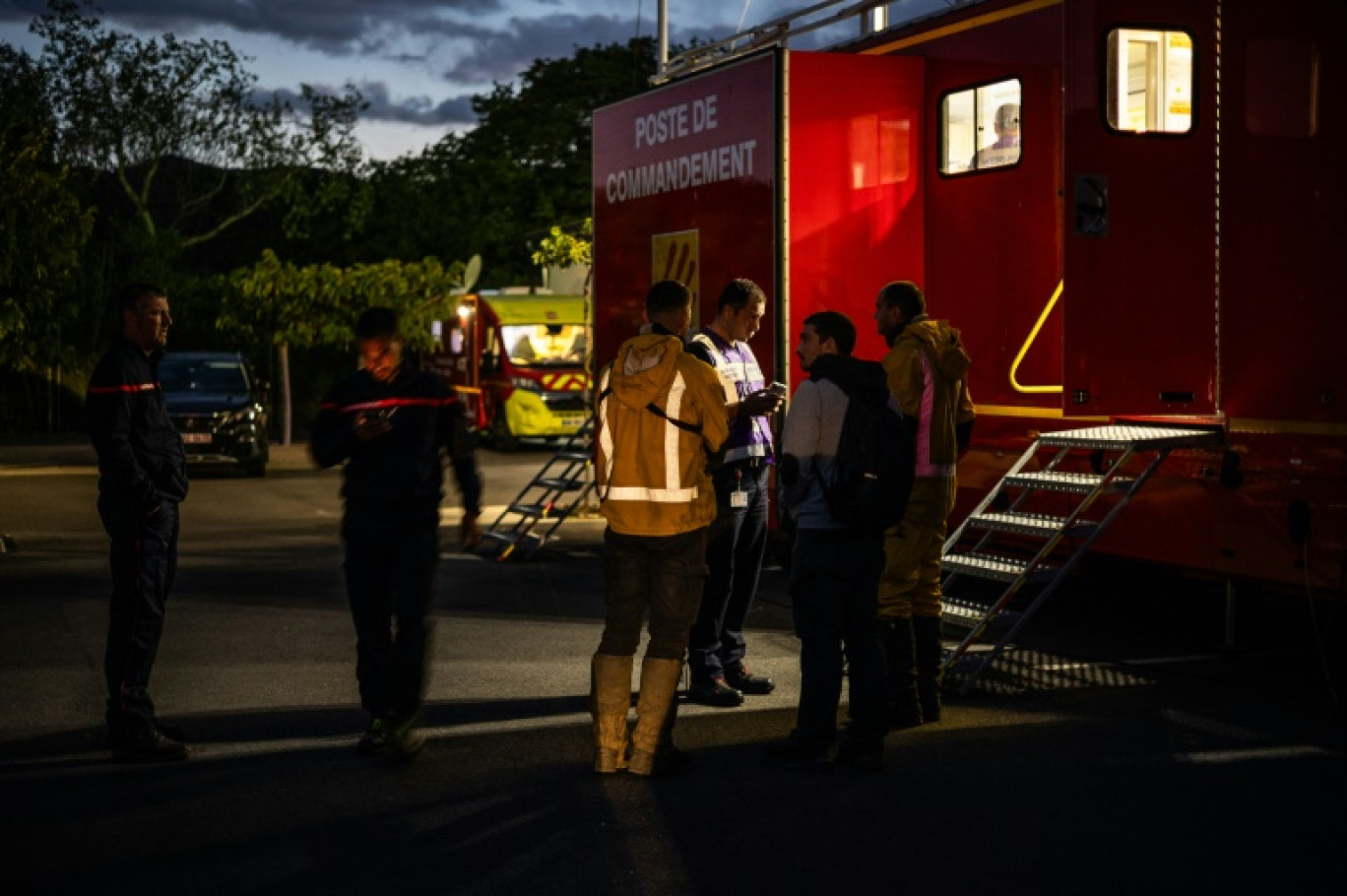 Des pompiers se tiennent devant un poste de commandement alors qu'ils interviennent sur le feu de forêt à Camelas, près de Perpignan, le 12 septembre 2024 © Jean-Christophe MILHET