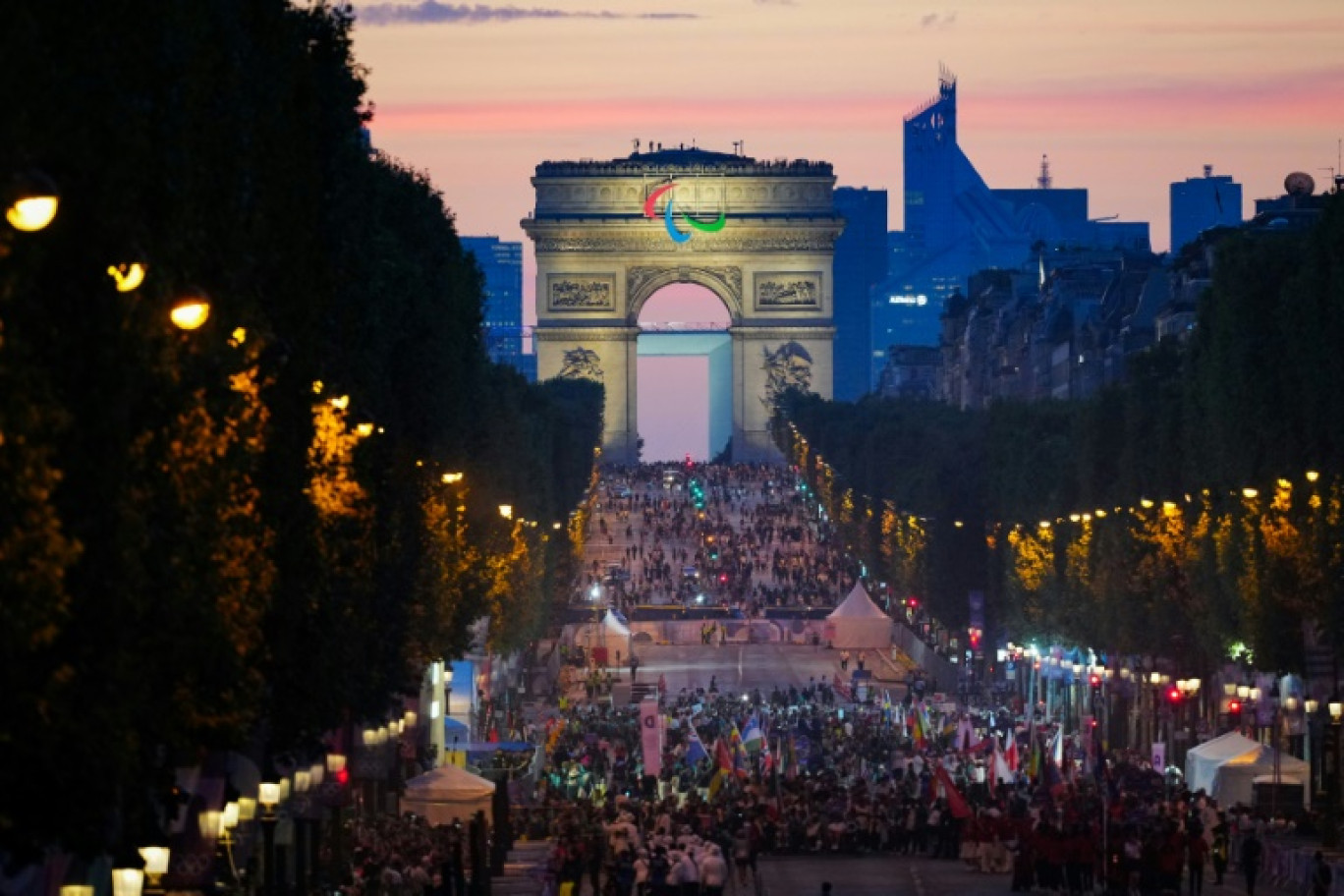 Le président français Emmanuel Macron se tient devant les anneaux olympiques, après avoir posé avec des athlètes français lors d'une visite au village olympique, à Saint-Denis, dans le nord de Paris, le 22 juillet 2024 © Michel Euler