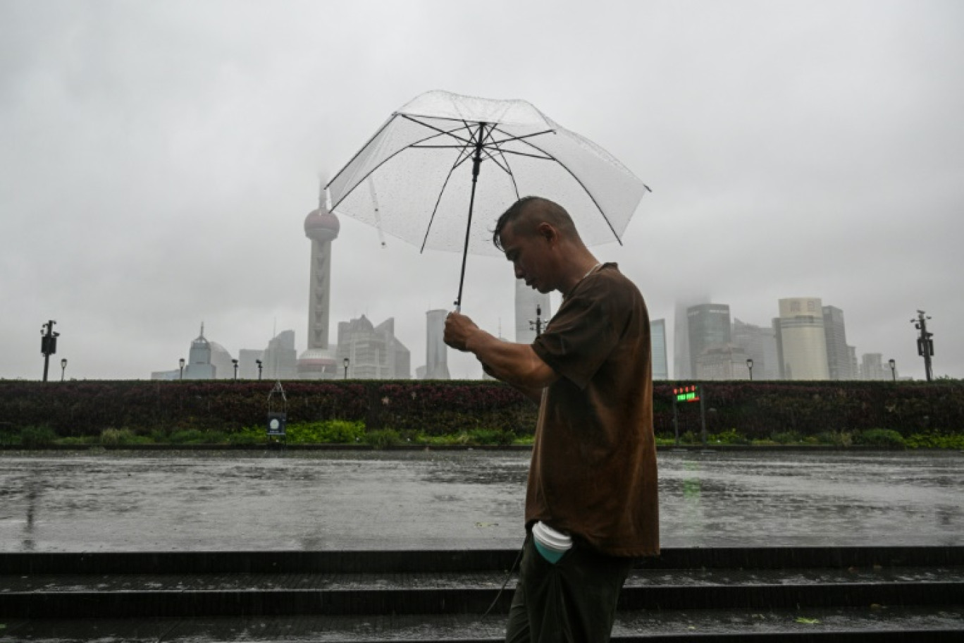 Un homme sous son parapluie lors du passage du typhon Bebinca à Shanghai, le 16 septembre 2024 © Hector RETAMAL