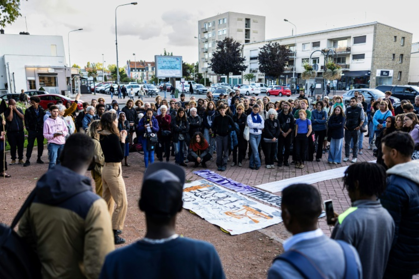 Des personnes autour d'une pancarte commémorant le nom des huit migrants décédés en tentant de traverser la Manche, à Calais, le 16 septembre 2024 © Sameer Al-DOUMY