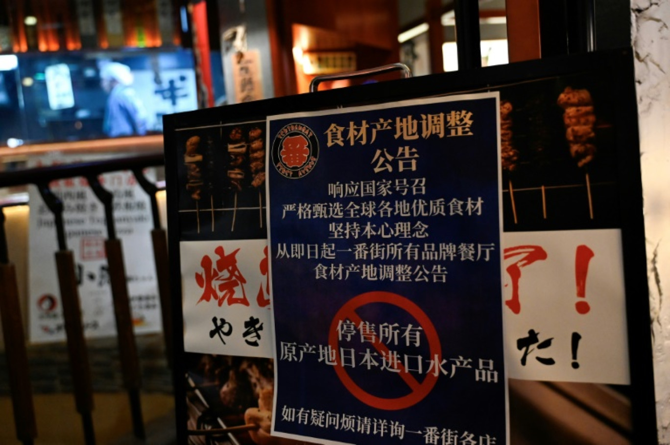 Une affiche informe les clients de "la suspension de la vente de tous les produits de la pêche importés du Japon" dans une zone de restaurants japonais à Pékin, le 27 août 2023 © Pedro PARDO