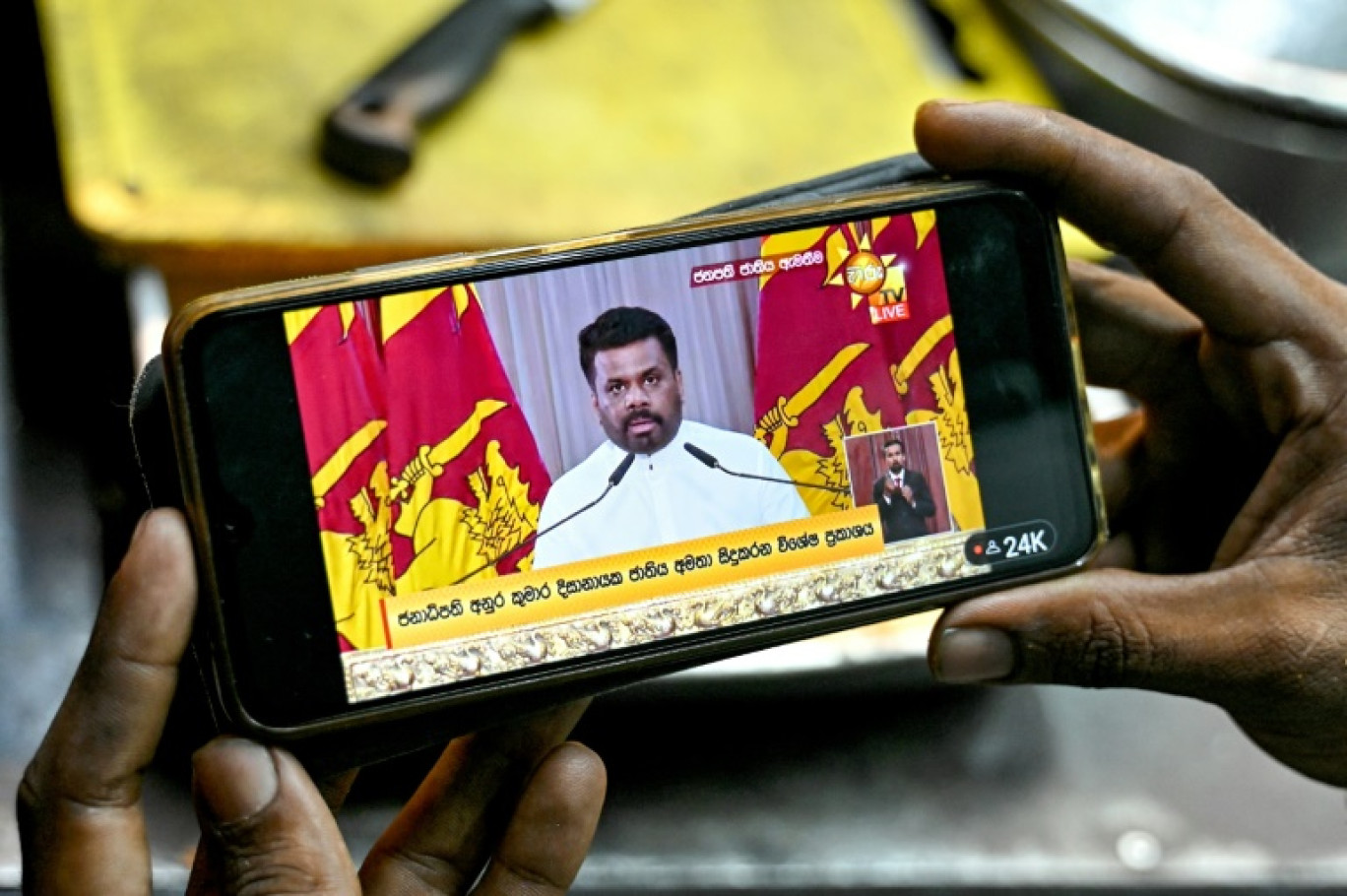 Un vendeur regarde l'allocution télévisée du nouveau président du Sri Lanka, Anura Kumara Dissanayake, à Colombo le 25 septembre 2024 © Idrees MOHAMMED