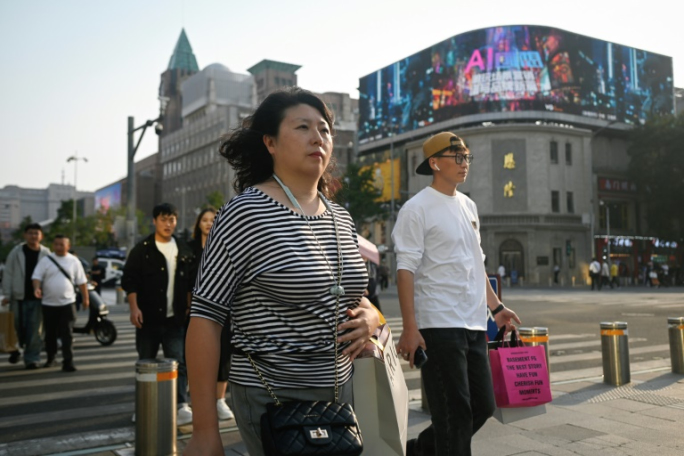 Des personnes traversent une rue dans un quartier d'affaires de Pékin, le 24 septembre 2024. © WANG Zhao