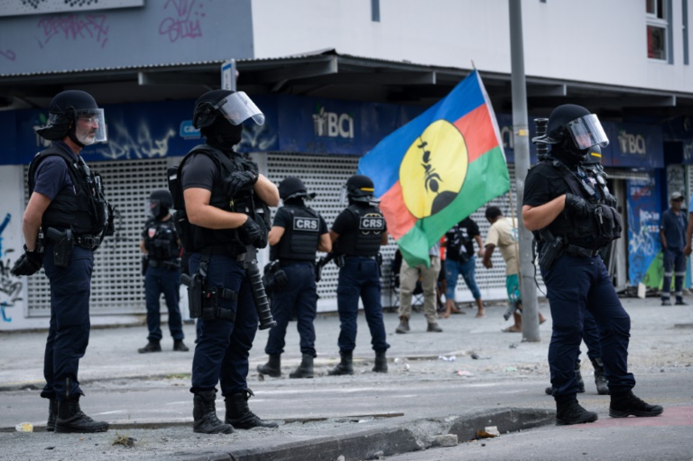 Un drapeau du FLNKS près d'une patrouille des Compagnies républicaines de sécurité (CRS) dans le quartier de La vallée du tir à Nouméa, lors de la fête de la citoyenneté en Nouvelle-Calédonie, le 24 septembre 2024 © SEBASTIEN BOZON