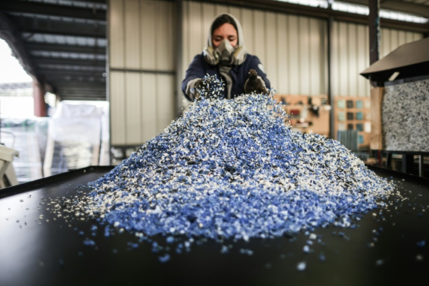 Julia Robert, co-fondatrice de l'association La Plastiquerie, manipule des déchets broyés destinés à produire des plaques de plastique recyclé pour fabriquer des objets de décoration, à Saint-Léon, près de Bordeaux, le 11 octobre 2024 © Thibaud MORITZ