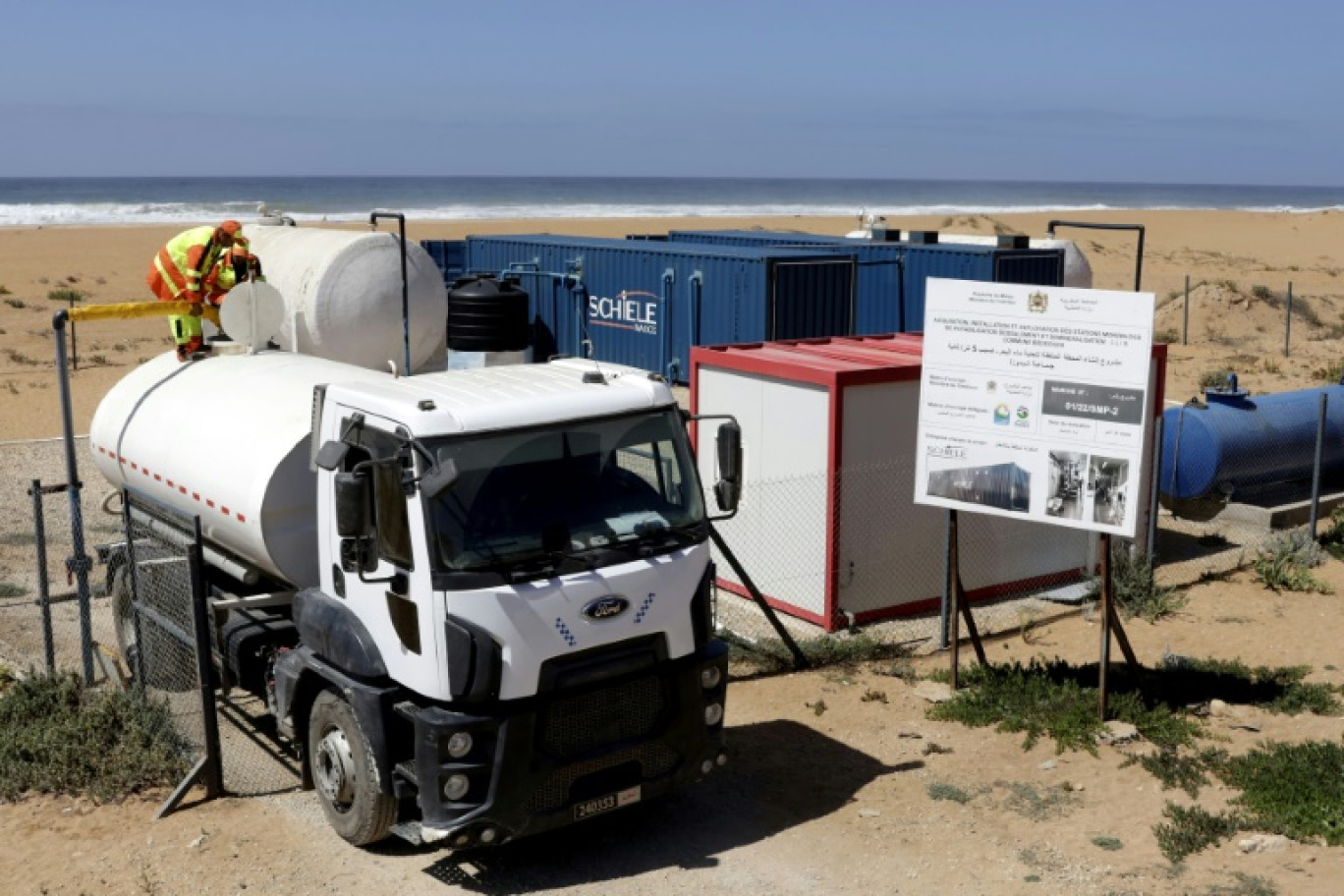 Un ouvrier remplit un réservoir d'eau traitée dans une station de dessalement mobile à Beddouza, dans l'ouest du Maroc, le 23 juillet 2024 © -