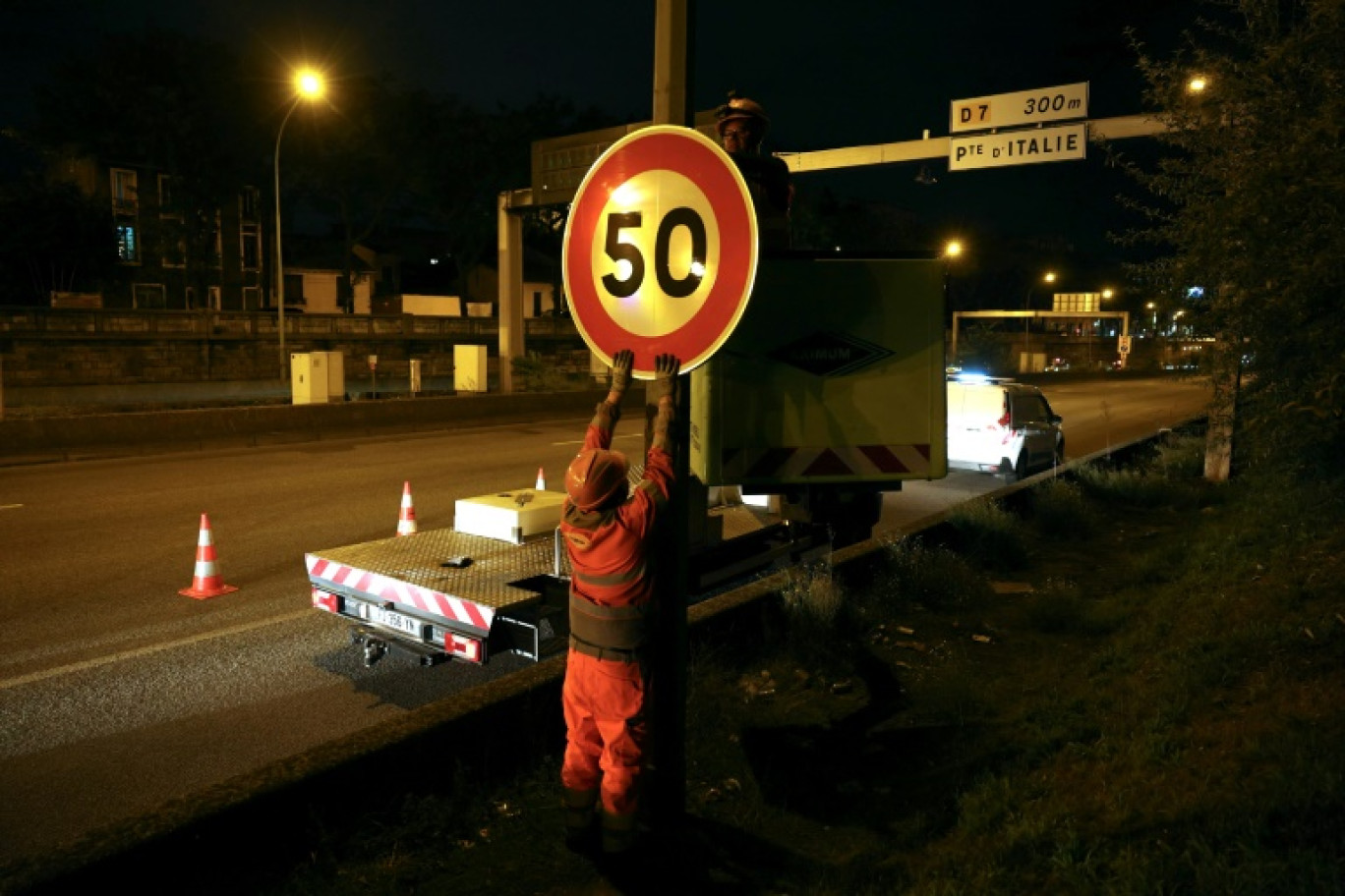 Un ouvrier installe un panneau de limitation à 50 km/h sur le périphérique au niveau de la porte d'Ivry, à Paris, le 30 septembre 2024 © Thomas SAMSON