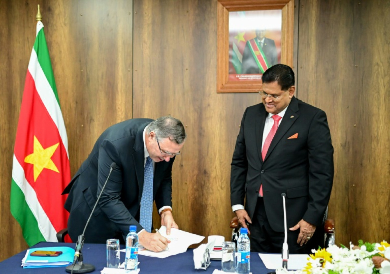 Photographie prise par le bureau du président du Suriname montrant le président Chan Santokhi (à droite) et le PDG du groupe français TotalEnergies Patrick Pouyanné signant des documents, le 1er octobre 2024 à Paramaribo © Handout