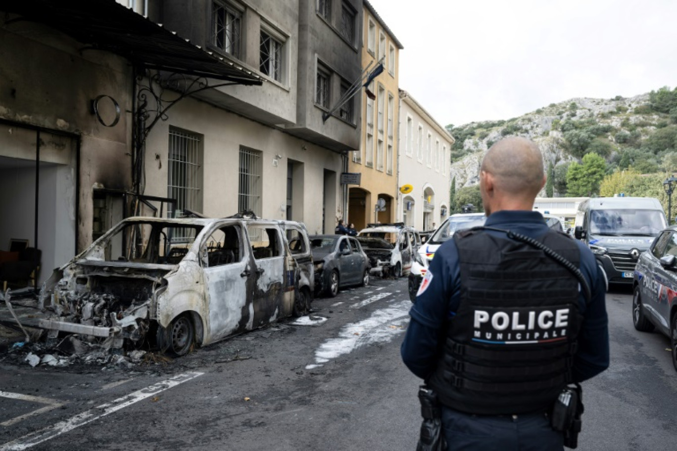 Un policier regarde des voitures incendiées devant le commissariat de Cavaillon, dans le Vaucluse, le 9 octobre 2024 © MIGUEL MEDINA