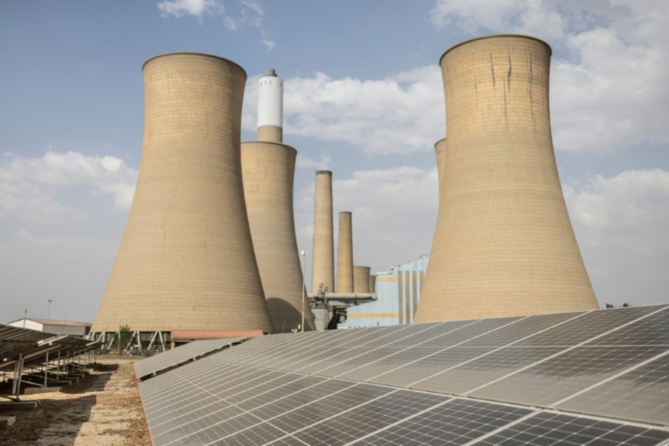 Vue générale des tours de refroidissement de la centrale de Komati en Afrique du Sud, le 9 septembre 2024, avec des panneaux solaires au premier plan © PAUL BOTES