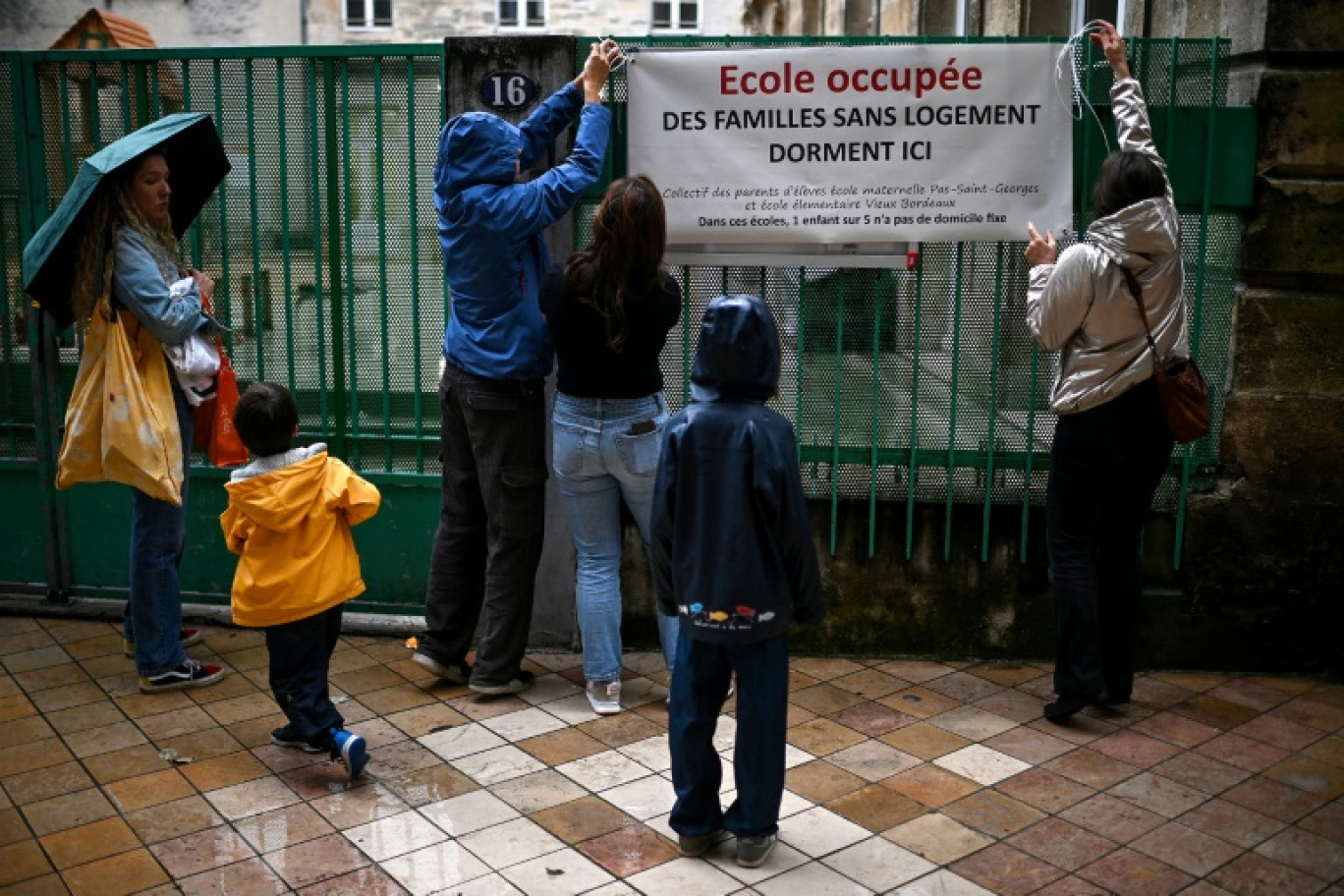 Des parents d'élèves attachent une banderole sur la clôture de l'école du Pas Saint-Georges, dans le centre de Bordeaux, le 9 octobre 2024 © Christophe ARCHAMBAULT