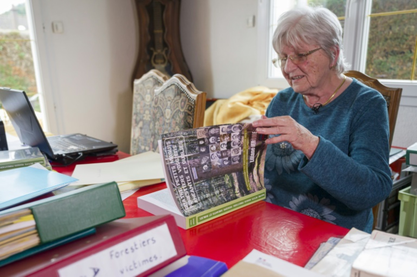 L'ancienne institutrice Liliane Jérôme, à son domicile avec son livre "Quatre petits maquis forestiers vosgiens anéantis et oubliés", le 30 septembre 2024 à Nompatelize, dans les Vosges © Jean-Christophe VERHAEGEN