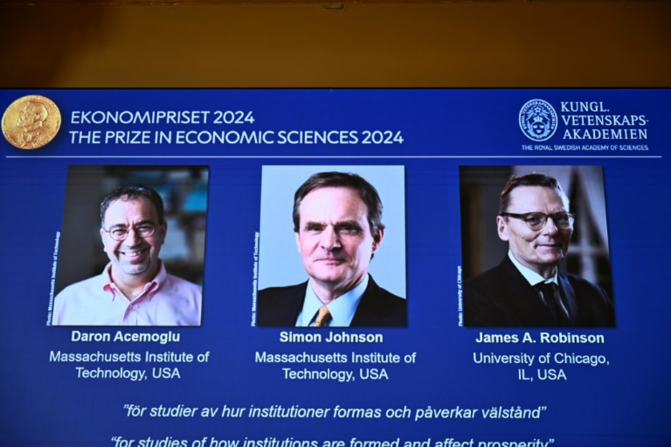 (g-d) Les portraits des lauréats du prix Nobel d'économie, l'Américano-turc Daron Acemoglu, et les Britano-américains Simon Johnson et James A. Robinson, à l'Académie royale des sciences de Suède, le 14 octobre 2024 à Stockholm © Christine OLSSON