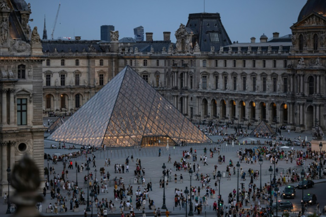 Des touristes se pressent autour de la Pyramide du Louvre, dessinée par l'architecte sino-américain Ieoh Ming Pei, à Paris, le 8 août 2024 © JOEL SAGET