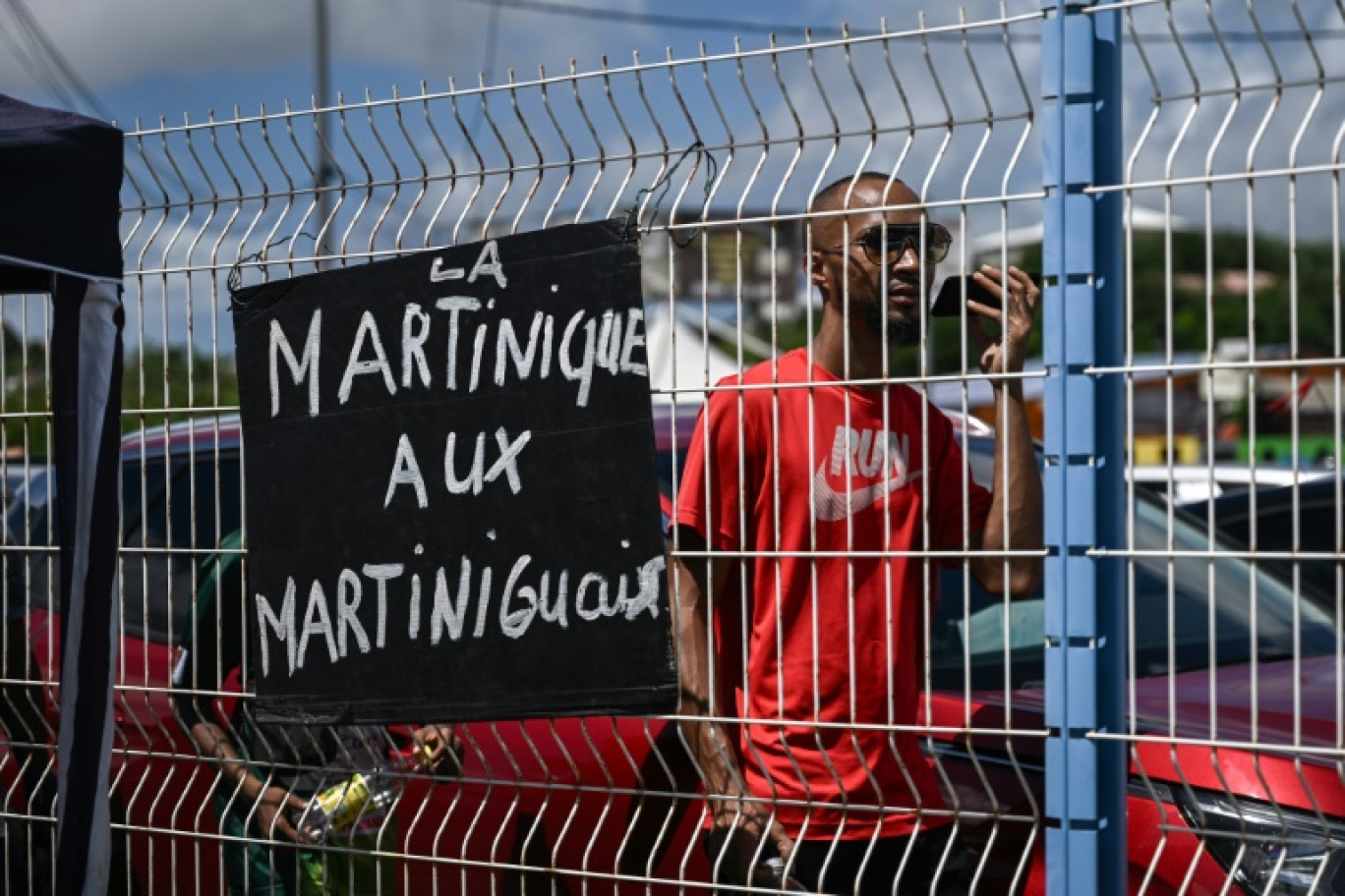 Un partisan du Rassemblement pour la protection des peuples et des ressources afro-caribéens (RPPRAC) marche derrière une pancarte sur laquelle on peut lire "La Martinique aux Martiniquais" à Fort-de-France, en Martinique, le 19 octobre 2024 © Philippe LOPEZ