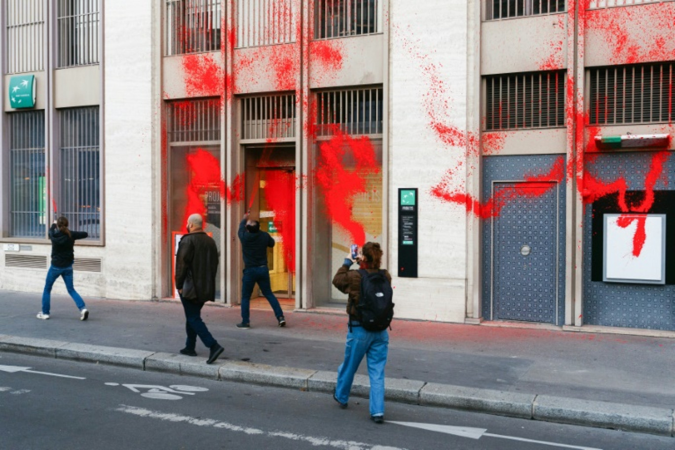 Des militants de l'association Action Justice Climat aspergent de peinture rouge la façade d'une agence du groupe BNP Paribas, le 24 octobre 2024 à Paris © Dimitar DILKOFF