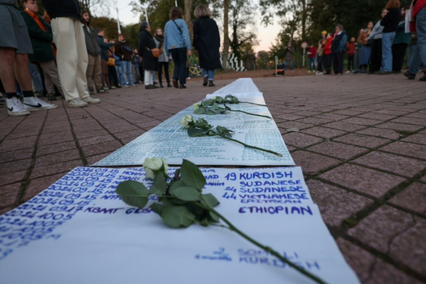 Des fleurs déposées sur une liste de migrants morts en tentant de traverser la Manche, lors d'un hommage à Calais, le 24 octobre 2024 dans le Pas-de-Calais © DENIS CHARLET