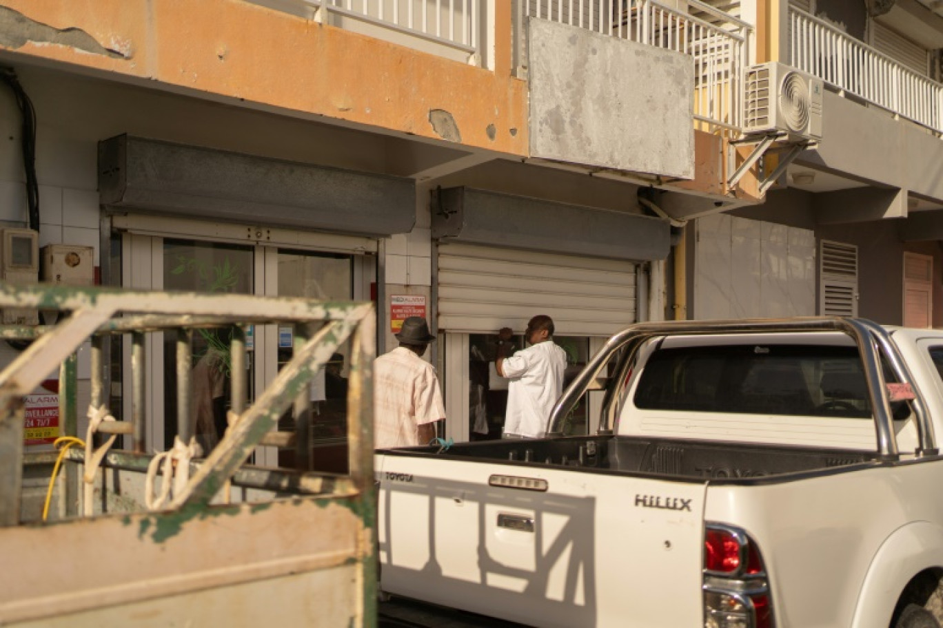 Un boucher ouvre manuellement son rideau métallique lors d'une panne d'électricité au Moule, en Guadeloupe, le 26 octobre 2024 © Brian Nocandy