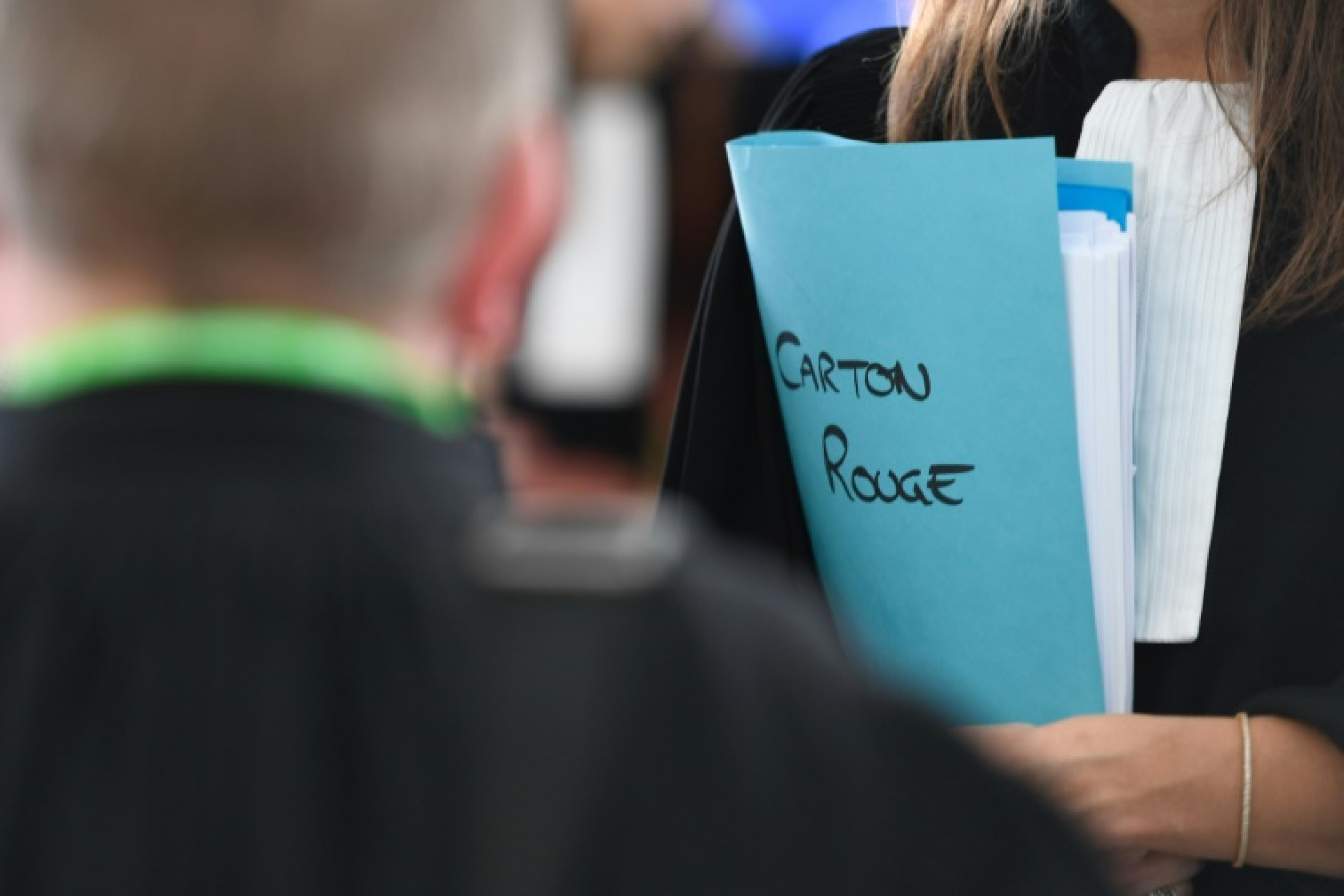 Une avocate tient un dossier portant l'inscription "Carton rouge" à l'ouverture du procès au centre des congrès à Nancy, le 21 octobre 2024 © Jean-Christophe VERHAEGEN