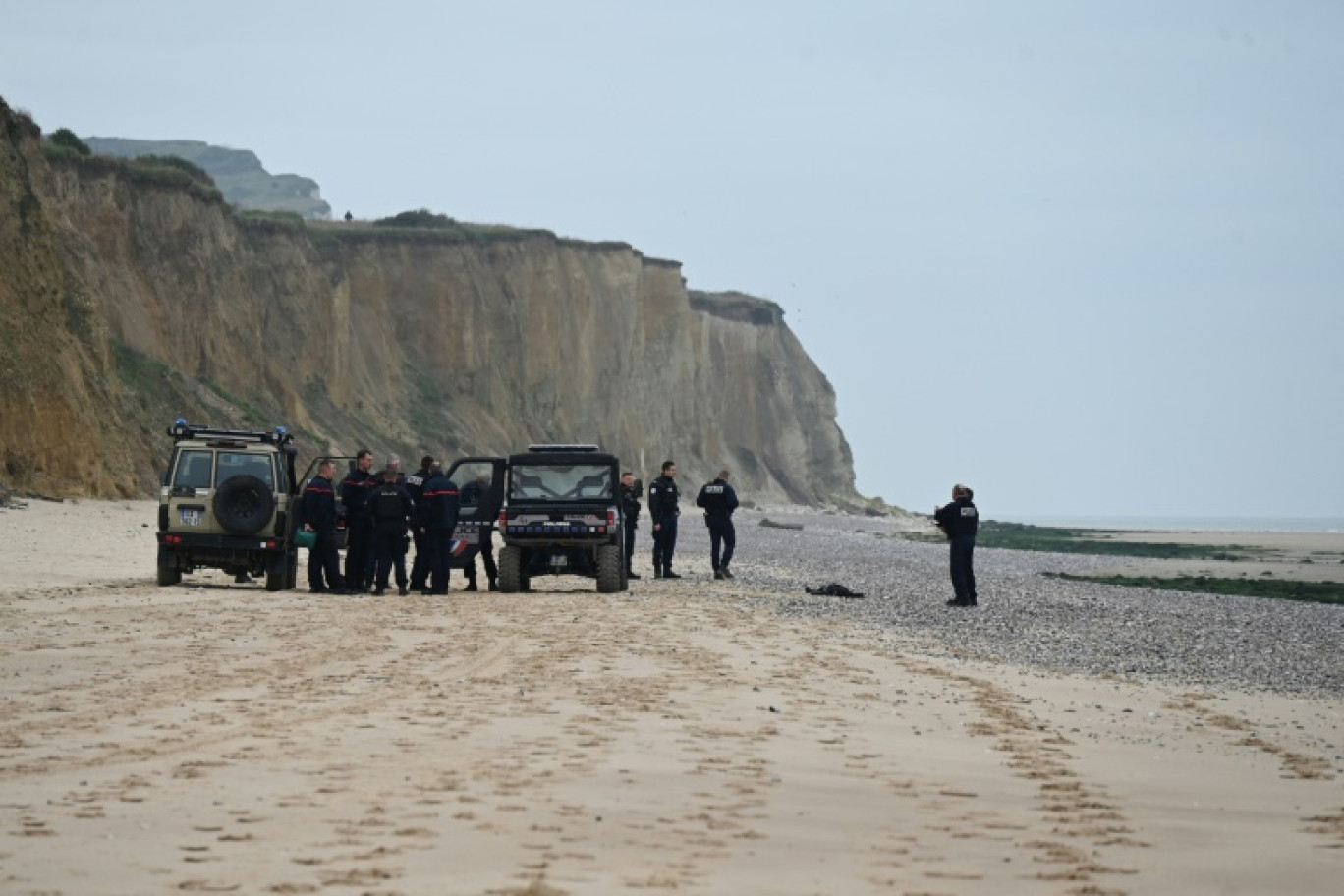 Des policiers près d'un corps découvert sur la plage de Sangatte, près de Calais, d'où de nombreux migrants tentent la  traversée de la Manche, le 2 novembre 2024 dans le Pas-de-Calais © Bernard BARRON