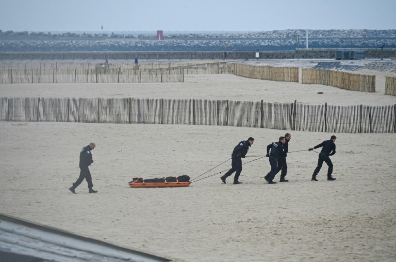 Des agents de police évacuent un corps découvert sur la plage de Calais, d'où de nombreux migrants tentent la périlleuse traversée de la Manche, le 6 novembre 2024 © Bernard BARRON