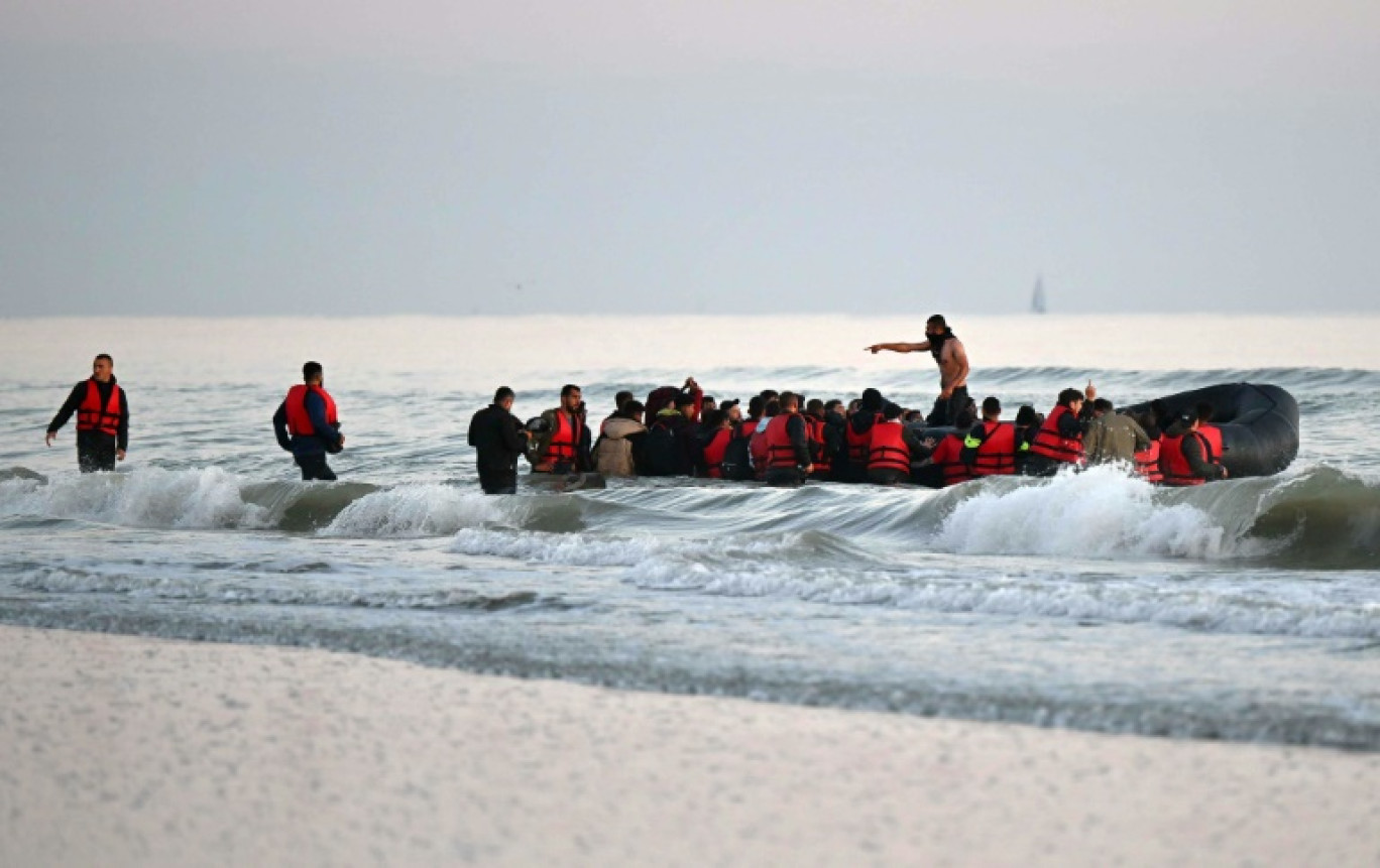 Un passeur (c) debout parmi des migrants à bord d'un bateau pneumatique pour tenter de traverser illégalement la Manche vers la Grande-Bretagne, le 11 juillet 2022 près de Gravlines, dans le Nord © Denis Charlet