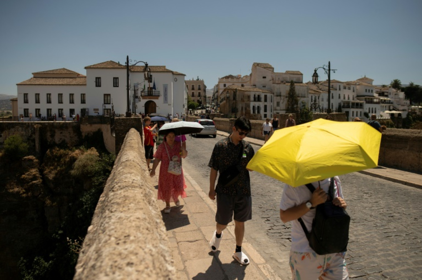 Des touristes se protègent du soleil sous des parapluies à Ronda lors d'une vague de chaleur, le 9 août 2024 en Espagne © JORGE GUERRERO