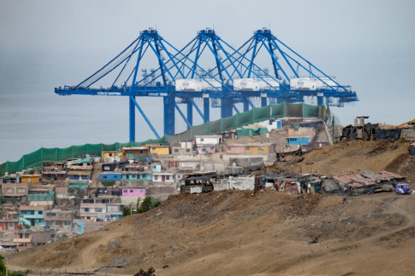 Vue des grues du mégaport de Chancay, derrière un quartier de la ville, au nord de la capitale péruvienne Lima, le 29 octobre 2024 © Cris BOURONCLE