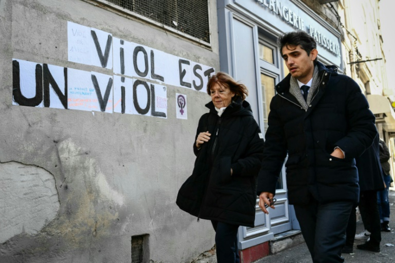 Gisèle Pelicot (gauche) marche au côté de son avocat Me Stéphane Babonneau près d'une inscription murale "Viol est un viol", le 14 novembre 2024 à Avignon © Christophe SIMON