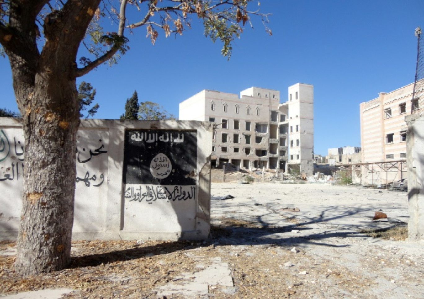 Le drapeau du groupe État islamique (EI) peint sur le mur à l'extérieur de l'ancien hôtel Minbij dans la ville syrienne de Manbij, qui a été utilisé comme prison lorsqu'il était sous le contrôle du groupe État islamique (EI), le 25 septembre 2016 
 IS overran Arab-majority Manbij in early 2014, imposing the hardline interpretation of Islamic law it has adopted across its self-styled "caliphate" straddling Syria and Iraq. © Ayham al-Mohammad